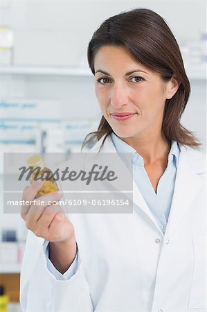 Happy female pharmacist holding a bottle of pills in a pharmacy