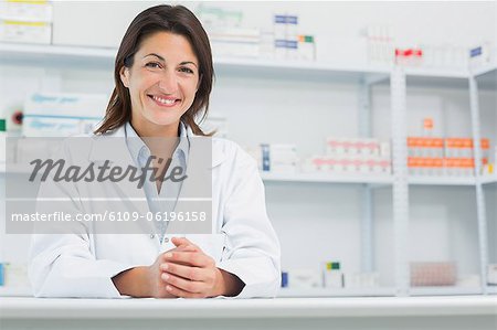 Smiling woman pharmacist behind a counter joining her hands