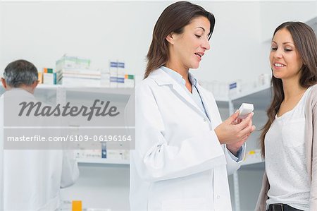 Pharmacist talking to a customer while holding pills