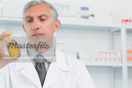 Male pharmacist looking at a flask of pills