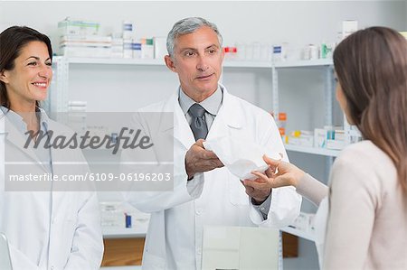 Smiling pharmacist with a colleague in front of a female client