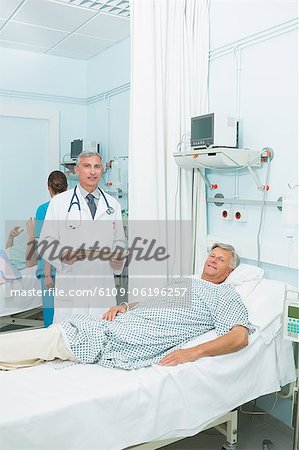 Smiling male doctor with a happy male patient in a bed ward
