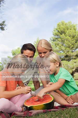 Young attractive family having watermelon at a picnic