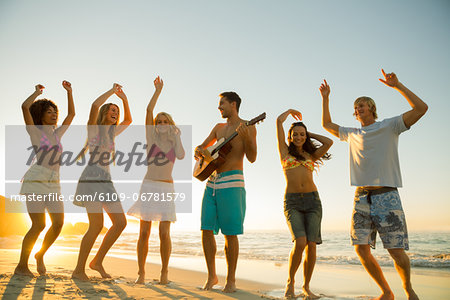 Friends having a party and playing guitar on the beach