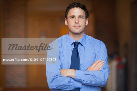 Content handsome lecturer looking at camera in hallway in a college