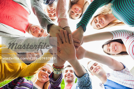 Group of smiling students putting hands in a circle on campus at the university Group of smiling students putting hands in a circle on campus at the university