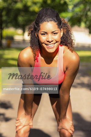 Tired healthy young woman taking a break while jogging in the park