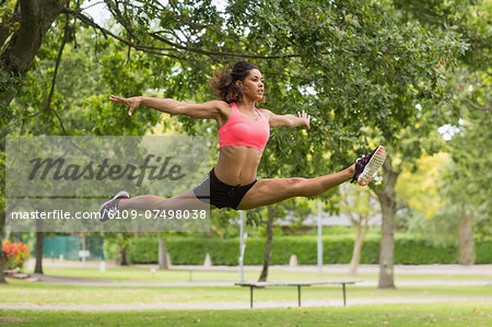 Full length of a toned young woman performing the splits jump in the park