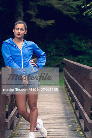 Full length of a healthy young woman standing on footbridge during exercise