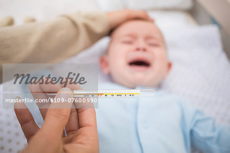 Mother examining ailing babys temperature