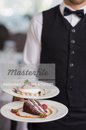 Waiter showing two dessert plates