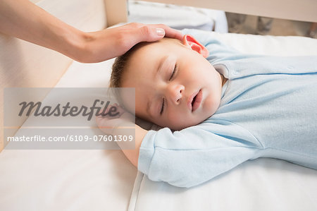 Mother watching over baby son sleeping in crib