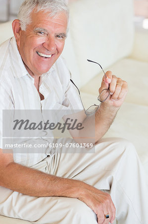Happy senior man sitting on the couch holding glasses