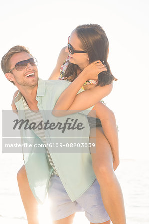 Lovely gay couple on piggyback ride at the beach. Stock Photo