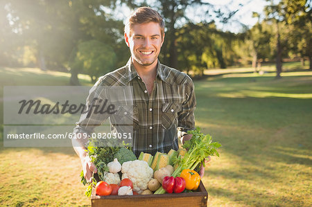 Smiling man carrying box of vegetables