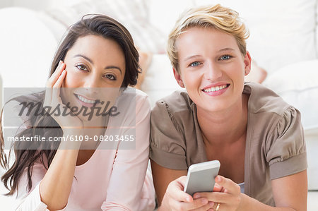 Portrait of smiling homosexual couple using smartphone and looking at camera