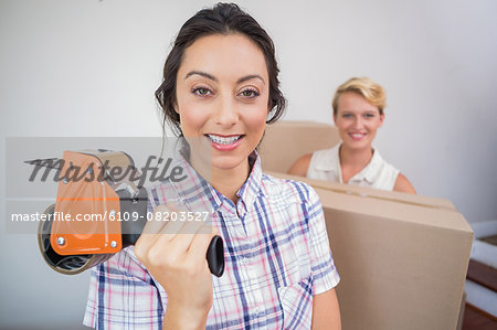 Smiling lesbian couple holding a tape sealing