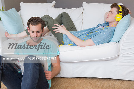 Homosexual couple reading a newspaper and listening music with headphones