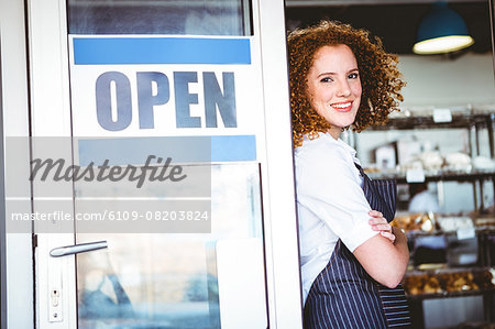 Happy pretty barista looking at camera with arms crossed