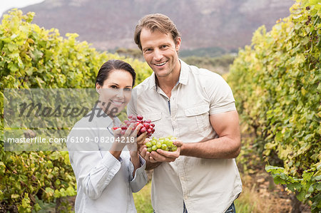 Smiling couple showing a bunch of grapes