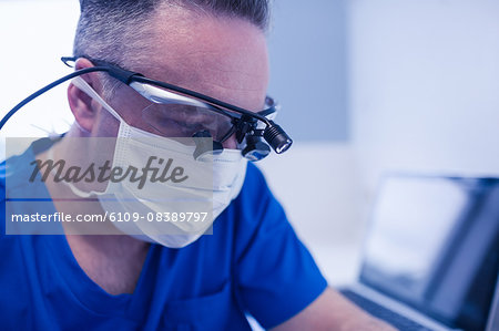Concentrated male dentist with dental loupes