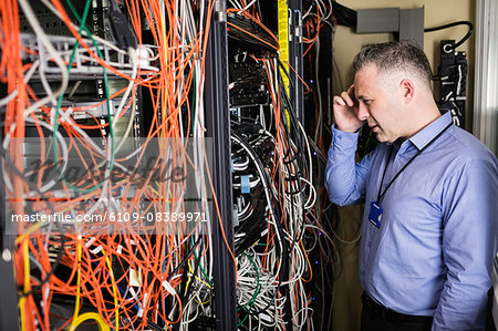 Technician using tablet pc while analysing server Technician using tablet pc while analysing server
