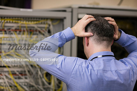 Stressed technician looking at open server locker
