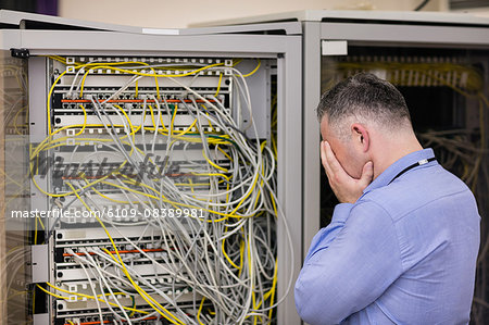 Stressed technician looking at open server locker Stressed technician looking at open server locker
