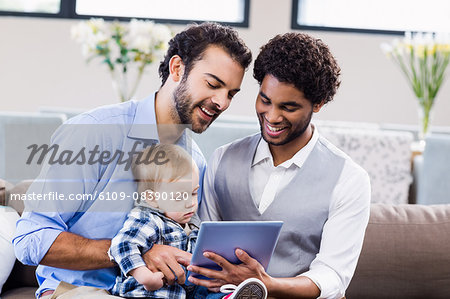 Happy gay couple with child using tablet Happy gay couple with child using tablet