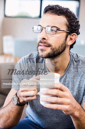 Close up of handsome man holding cup looking away