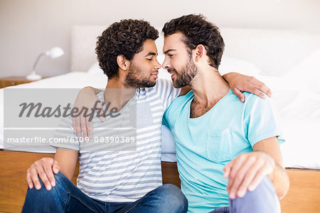 Happy gay couple sitting on the floor