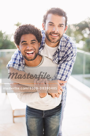 Lovely gay couple on piggyback ride at the beach. Stock Photo