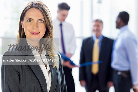 Businesswoman posing while her colleagues in background