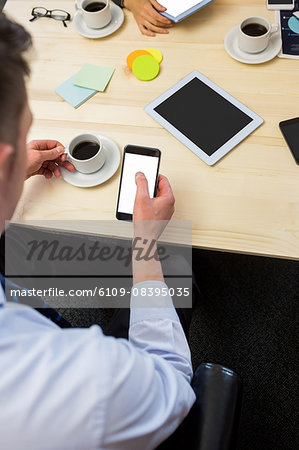 Businessman using his smartphone with coffee