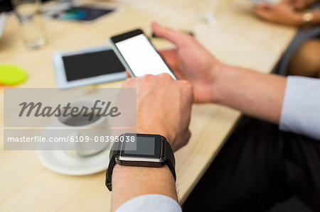 Businessman using his smartphone and his watch