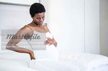 Smiling pregnant woman sitting on her bed