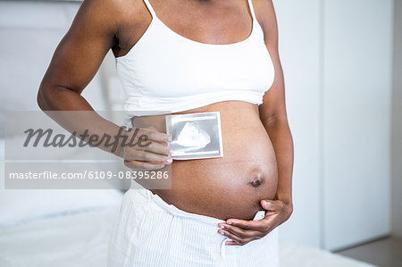 Pregnant woman holding ultrasound by her stomach