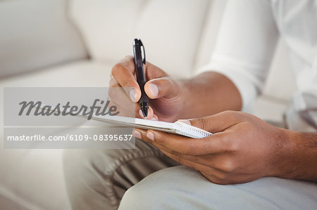 Male therapist writing on book at clinic