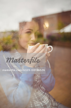 Pretty student sitting by the window having coffee