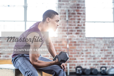 Serious muscular man lifting dumbbell