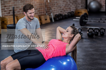 Trainer assisting woman with abdominal crunches