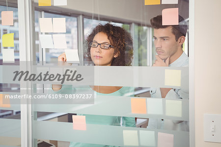 Businesswoman writing on adhesive note in office
