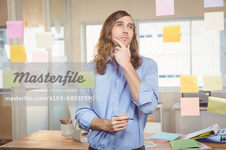 Thoughtful businessman looking at sticky notes
