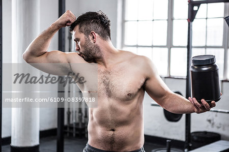 Shirtless young man drinking protein shake in gym Photograph by