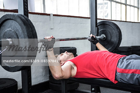 Fit man lifting heavy barbell