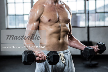 Fit shirtless man lifting dumbbells