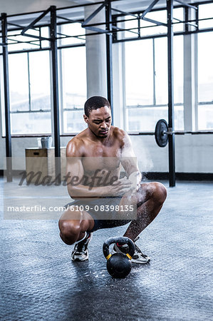 Fit shirtless man chalking his hands