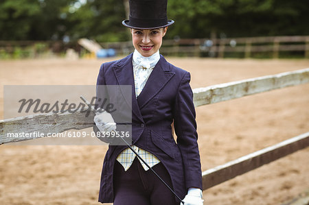 Smiling jockey with whip posing for camera