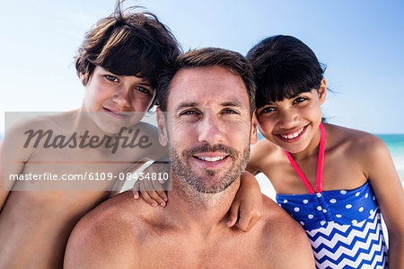 Father and children looking at camera on the beach