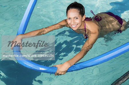 Happy pregnant woman exercising in the pool at the leisure center